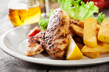 Grilled chicken breasts served with fries and fresh salad