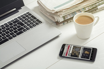 news on smartphone screen, laptop, milk coffee and newspapers on office - obrazy, fototapety, plakaty