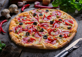 Freshly baked pizza with feta cheese, olives, salami and paprika