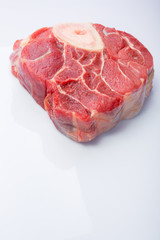 one piece of raw beef meat with the bone in the middle on a white background