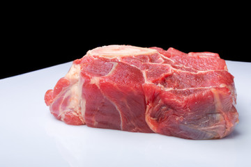 one piece of raw beef meat  on black background