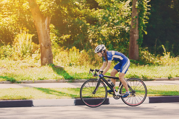 Female cyclist rides a racing bike on road - obrazy, fototapety, plakaty