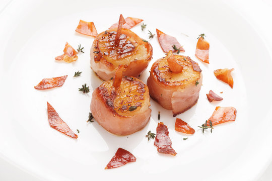 Scallops fried in bacon on plate, close-up