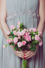 Wedding bouquet of flowers, young bridesmaid holding a bouquet of pink roses.