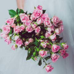 Wedding bouquet of flowers, young bride holding a bouquet of pink roses. Image of wedding dress and pink bouquet.