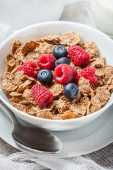 Bowl of cereals with blueberries and raspberrie.