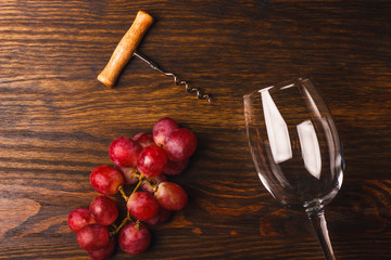 Empty glass for wine, corkscrew and grapes