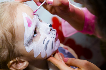  Woman draws on a child's face