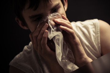 Teen inhaling narcotics from plastic bag
