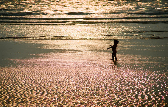 Fototapeta silouette of a little baby girl in front of brightly lighted sea