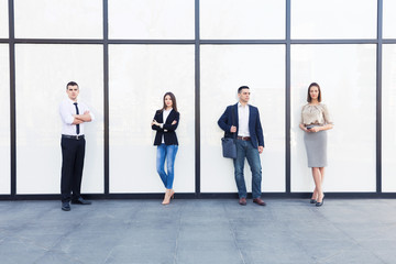 Four young business people standing in front of contemporary office building