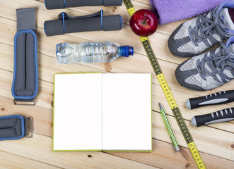 Dumbbells, Jump Rope, Towel, Sport Shoes, Ankle Weights, Tape Measure, Apple, Bottle Of Water, Notepad To Workout Plan On Wooden Floor. Sport Fitness Background.