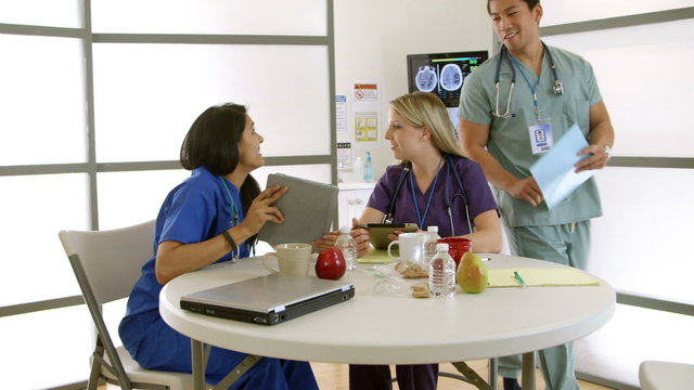 A young Asian intern walks into hospital break room and discusses issue with his fellow interns.