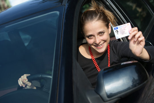 smiling girl in the car showing her driver's license