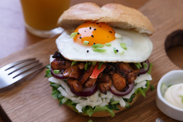 Homemade burger with fried egg and spicy fries on wood board