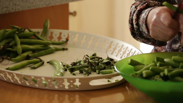 Houswife prepare pods ( broad bean ) for dinner at home