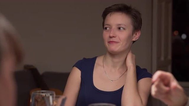 Young Russian woman in a dinner with friends. She is talking and smiling. The camera moves and focus changes to the man at foreground. 4K, UHD