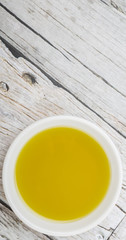 Avocado oil in white bowl over wooden background