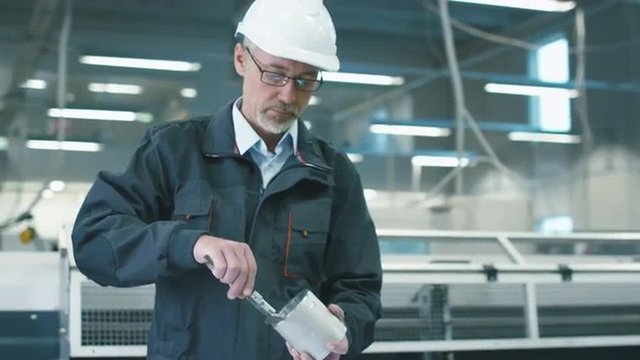  Senior engineer in hardhat is measuring metal objects and records data with a tablet computer in a factory. Shot on RED Cinema Camera.