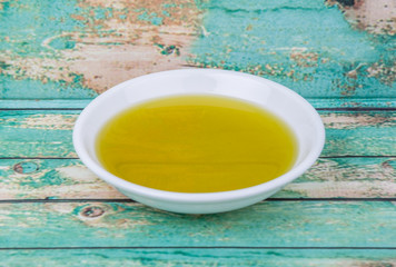 Avocado oil in white bowl over wooden background
