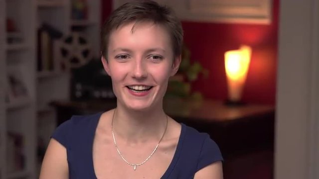 Young Russian woman talking with someone and smiling with a home background at night. The camera moves. 4K, UHD