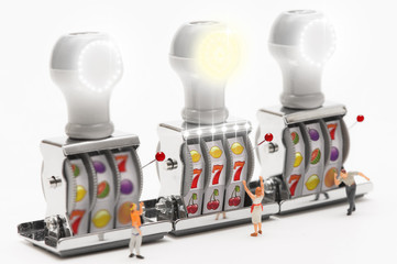 Miniature people playing slot machine.