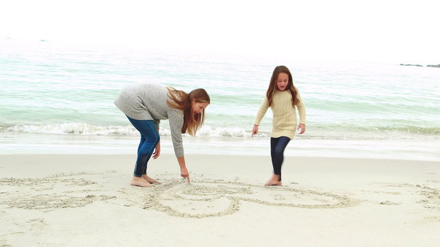 Mother and daughter drawing on the sand
