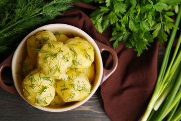 Boiled potatoes with greens in bowl on table close up