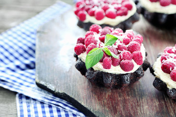Sweet cakes with raspberries on wooden table background