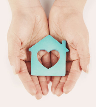 Female hands with model of house on light background