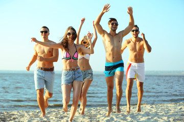 Happy friends running at the beach, outdoors