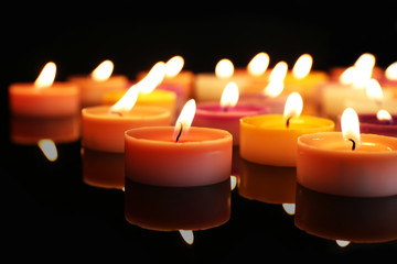 Many burning small candles on dark background, close-up