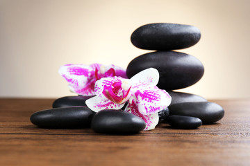 Fototapeta na wymiar Black pebbles with orchid on wooden table