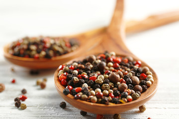 Two wooden spoons with pepper on the table, close-up
