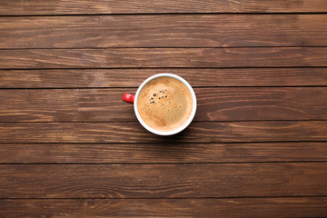 Cup of coffee on wooden table, top view