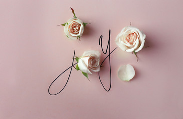 Inscription joy with beige roses on pink background
