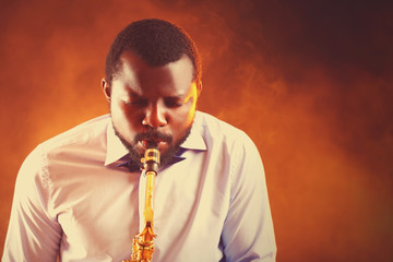 African American jazz musician playing the saxophone on ginger background