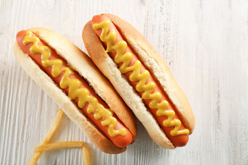 Hot dogs and fried potatoes on wooden background