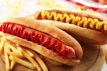 Hot dogs and fried potatoes on wooden cutting board closeup