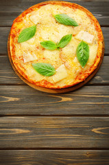 Tasty pizza decorated with basil  on wooden background, close up