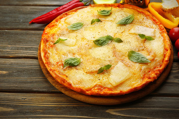 Tasty pizza decorated with basil and vegetables on wooden background, close up
