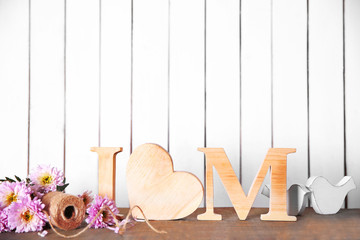 Obraz na płótnie Canvas Wooden letters with heart and flowers on white wall background