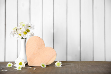 Fototapeta na wymiar Wooden heart with flowers on a white wall background