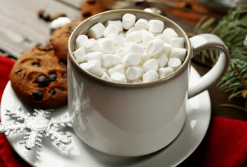 Mug of hot chocolate with marshmallows, fir tree branch on wooden background