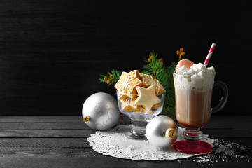 Cup of coffee with whipped cream and sweets on black table