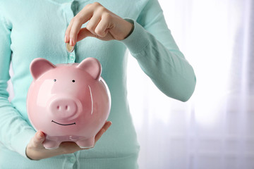 Woman putting euro coin into a piggy bank. Financial savings concept