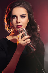 Portrait of beautiful singing woman on red background, close up