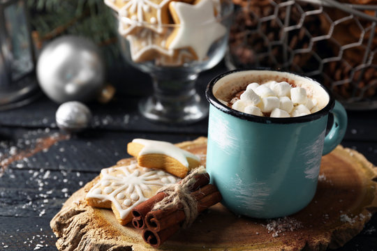 Mug of hot cacao with marshmallow and cookies on black table