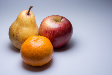 Pear, apple, and tangerine grouped, isolated on light grey background