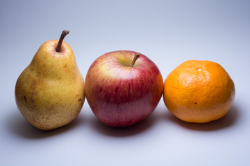 Pear, apple, and tangerine grouped, isolated on light grey background